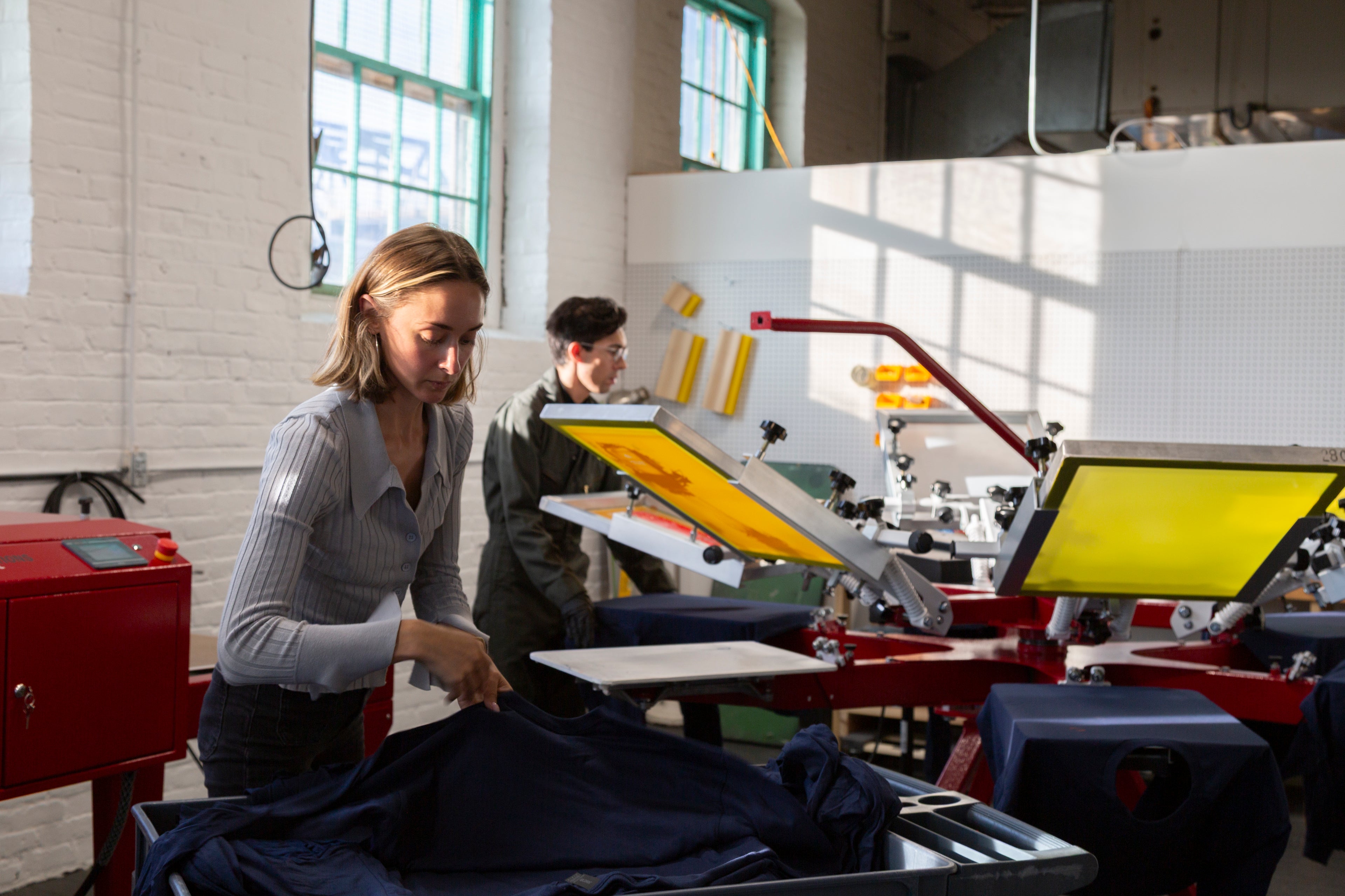 Frontside Factory staff screen printing custom shirts in a historic mill building in Fall River MA
